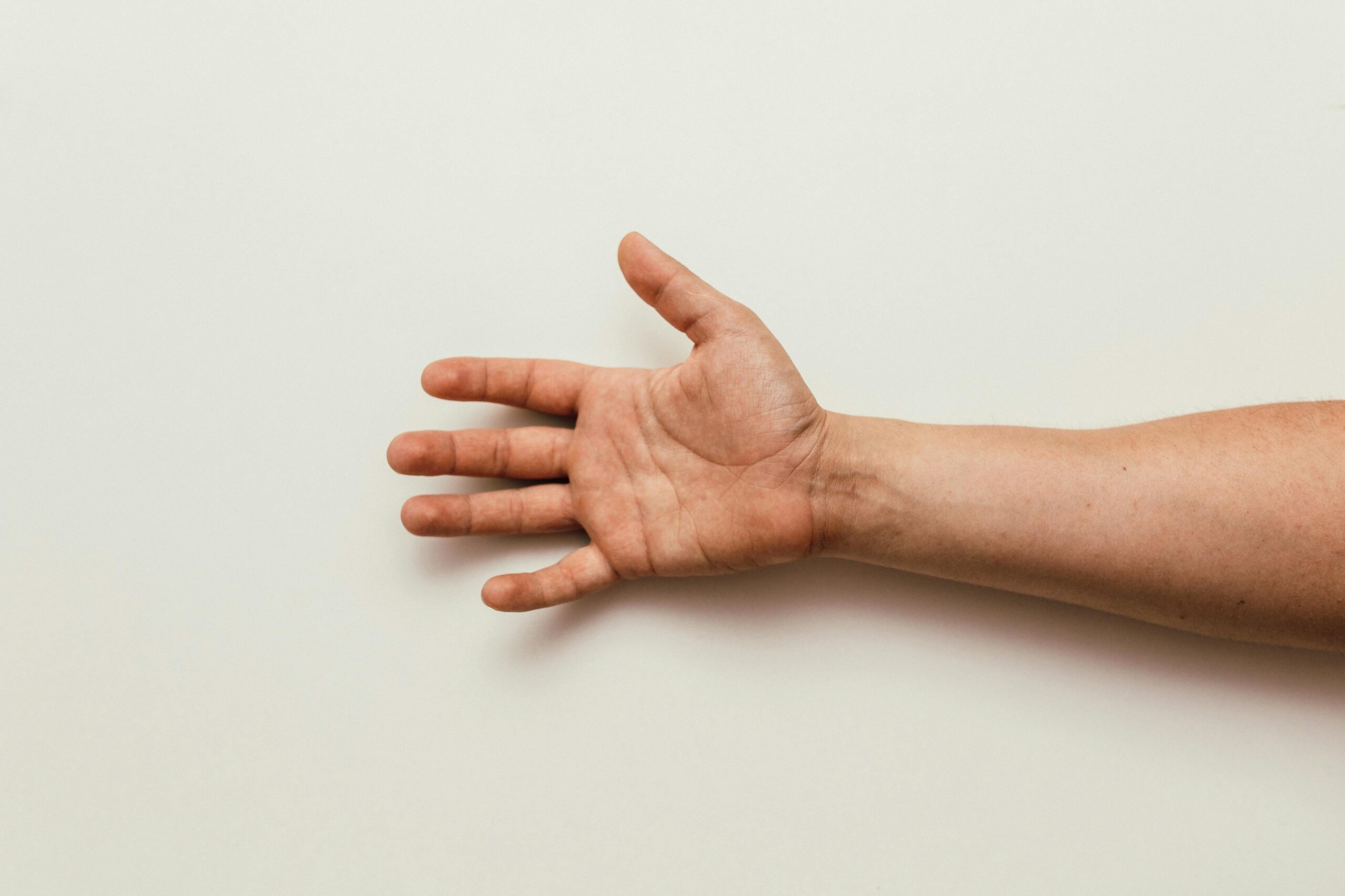 An outstretched human hand with open palm isolated on a plain white background.